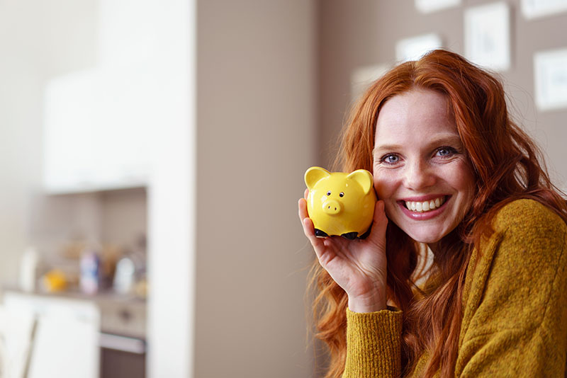 Woman smiling holding a piggy bank