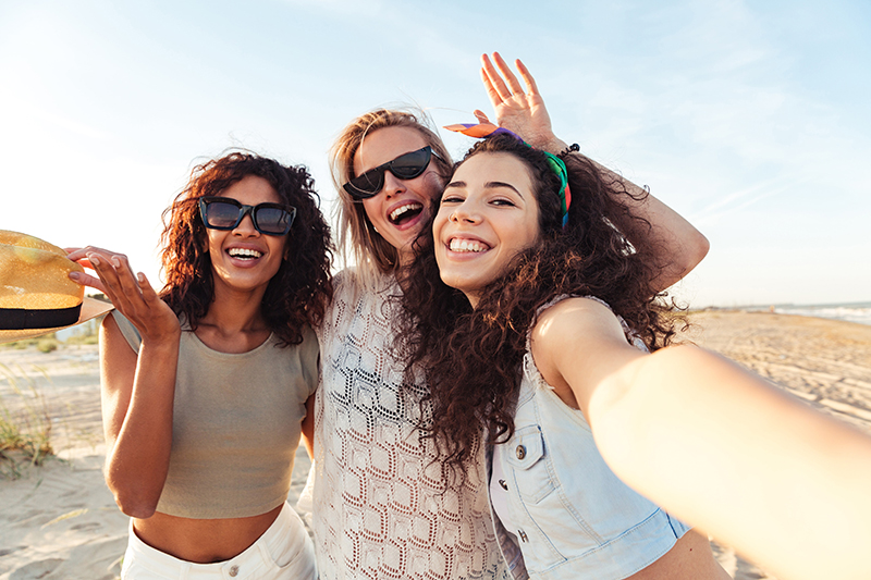 Three smiling women taking a selfie on the beach