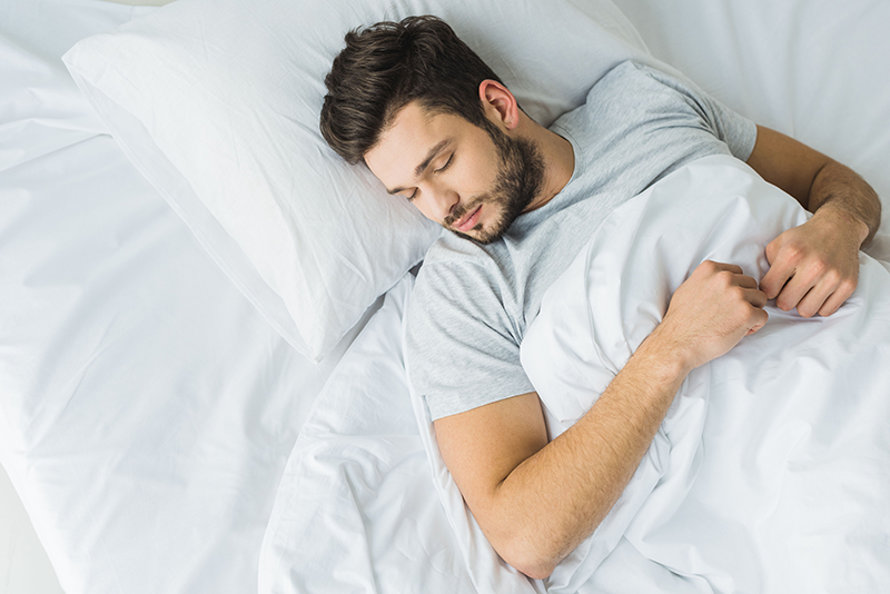 View of man sleeping on bed.