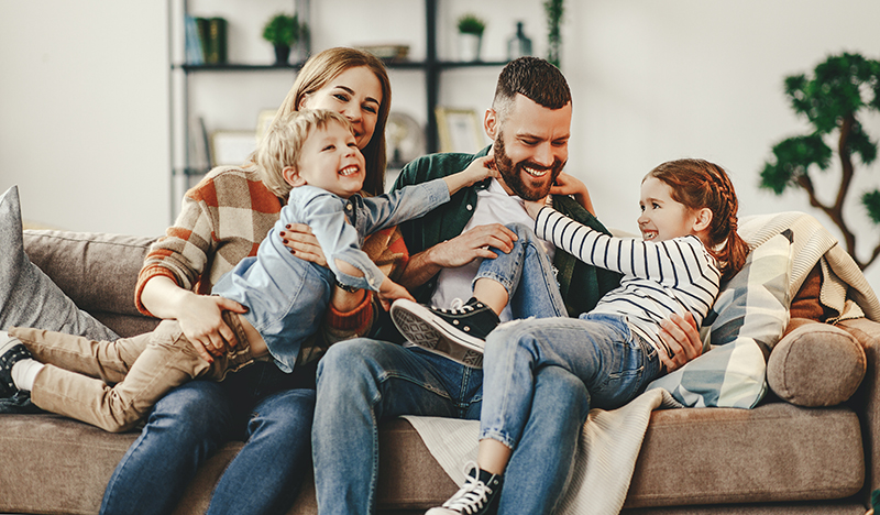 Happy family, parents and kids at home on the couch.