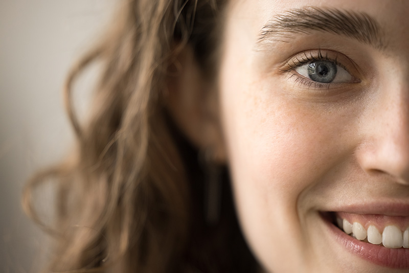 The image is a close-up photo of a person's face, focusing on one eye and their smile. It captures the details of the eye and the surrounding area, emphasising natural beauty and expression.